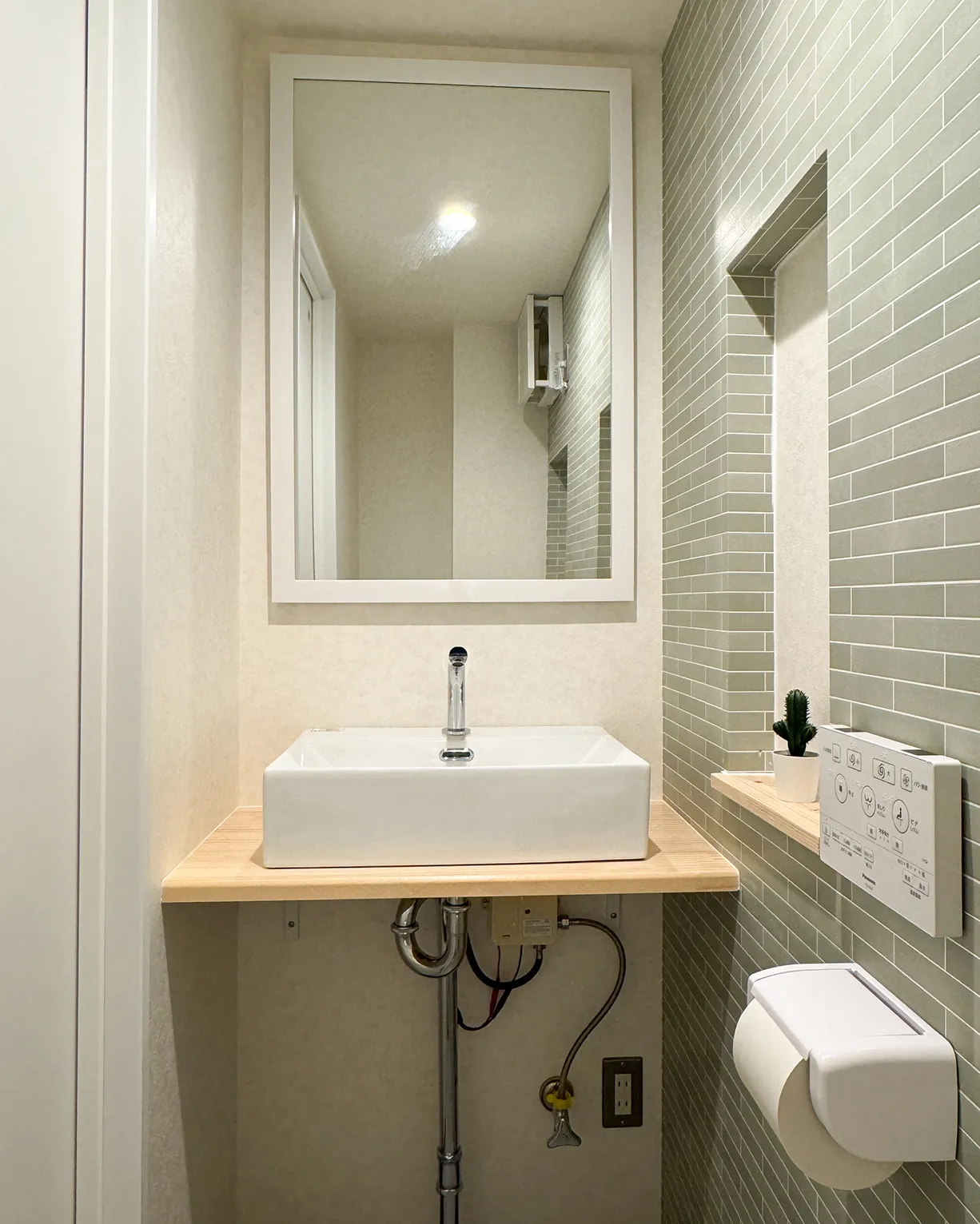 トイレ洗面。大型ミラー（61x9cm）と自動水栓手洗い。